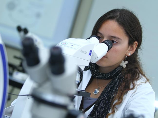 Mujer observando a través de un microscopio